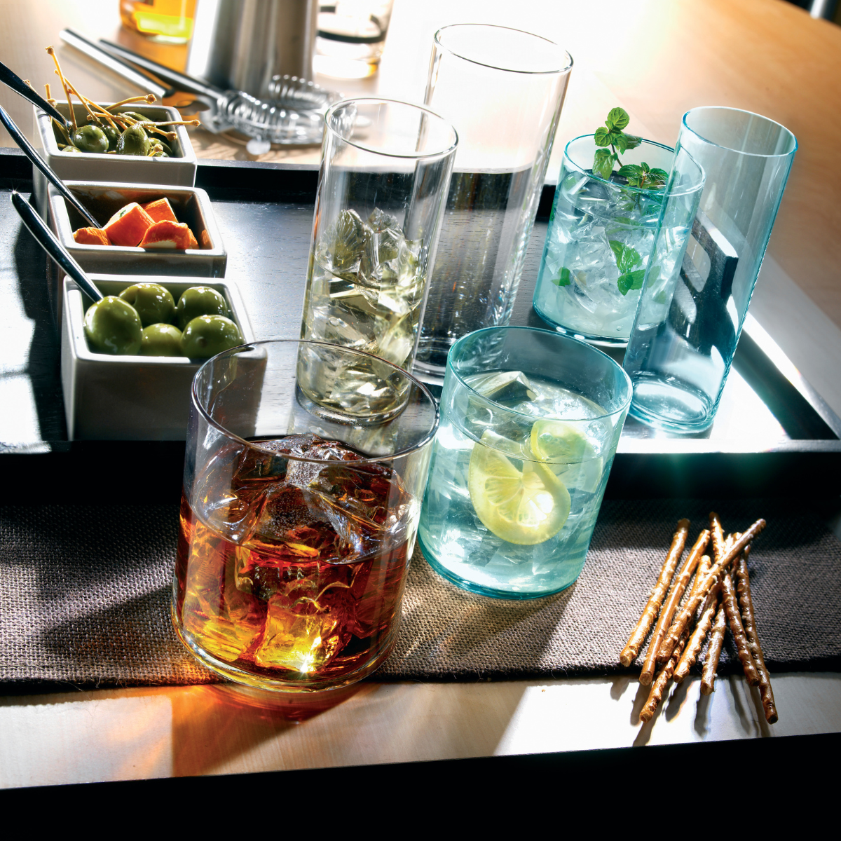 Set of 12 Bormioli Rocco Aere 290ml clear glass tumblers for water, shown in a stylish lifestyle setting.