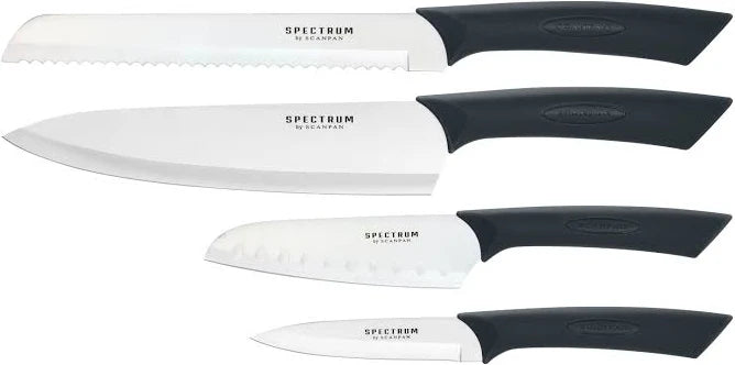 Scanpan Spectrum 4-piece black knife set featuring stainless steel blades and black handles on a kitchen countertop.